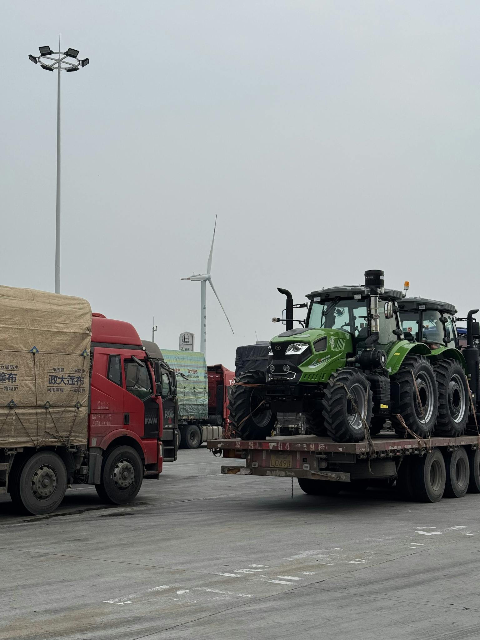 Heavy-duty trucks transporting equipment near wind turbines on a cloudy day.