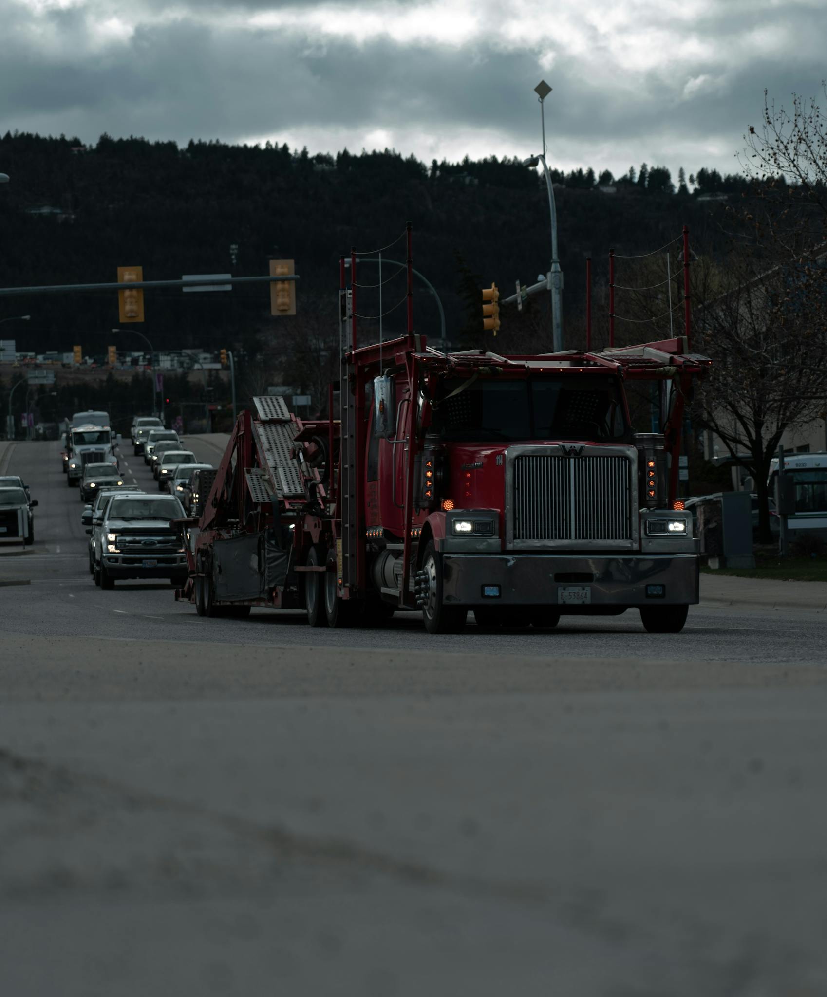 Street scene with trucks and cars under cloudy skies, highlighting urban traffic and transportation.